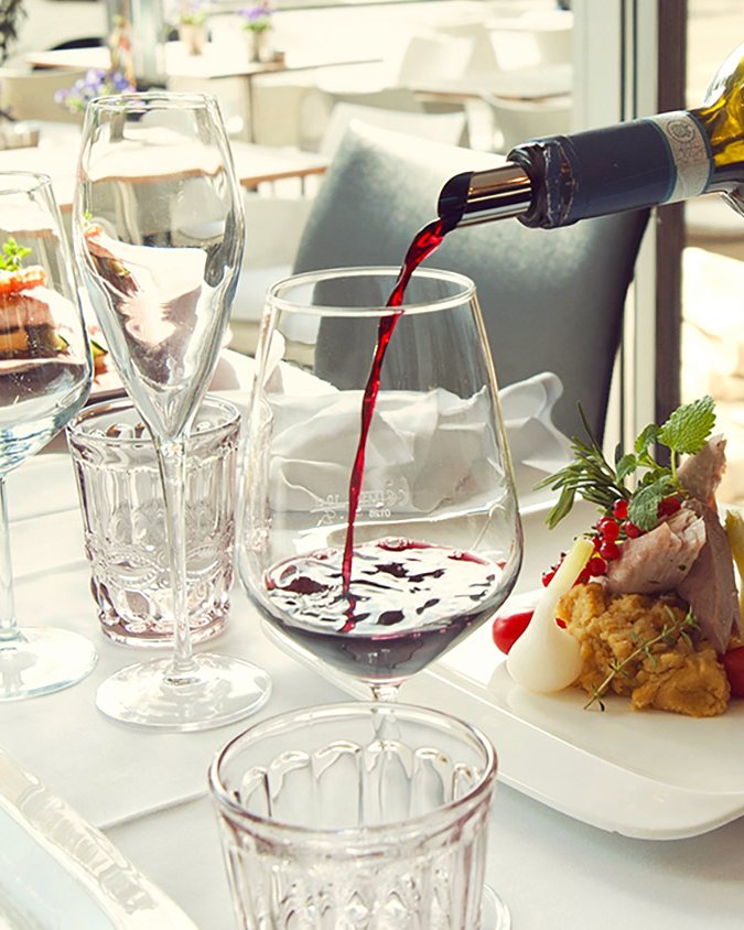 Ein Glas Rotwein wird am Tisch eingeschenkt