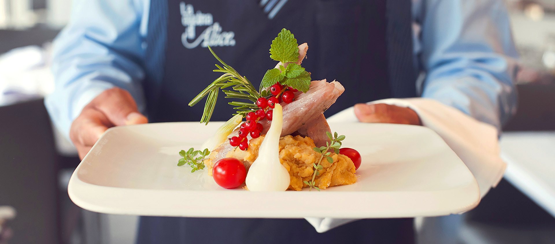 Ein Teller auf dem Weg in den Saal, mit der Schürze von La Cucina di Alice